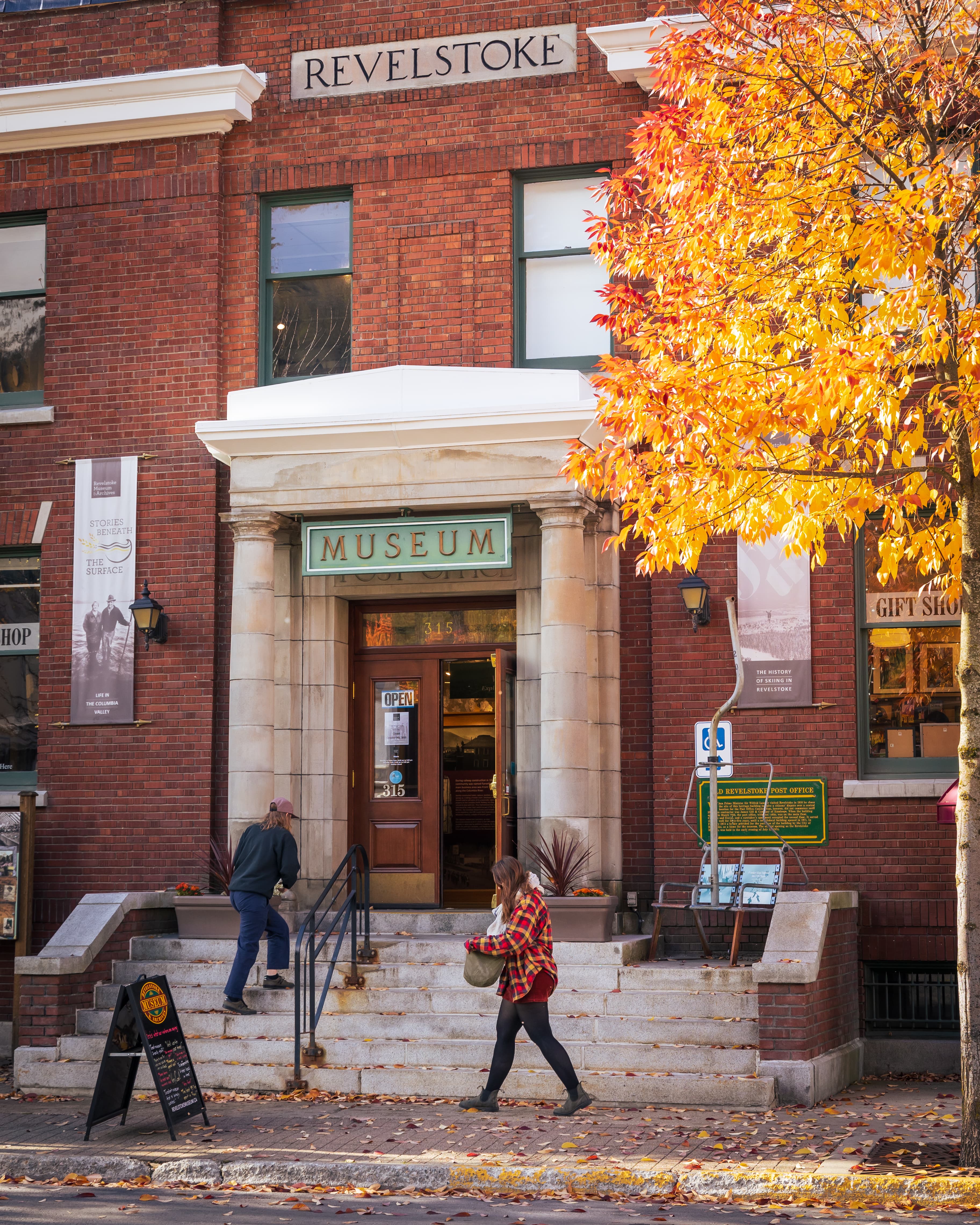 two girls walking into museum with maple leaves falling from nearby