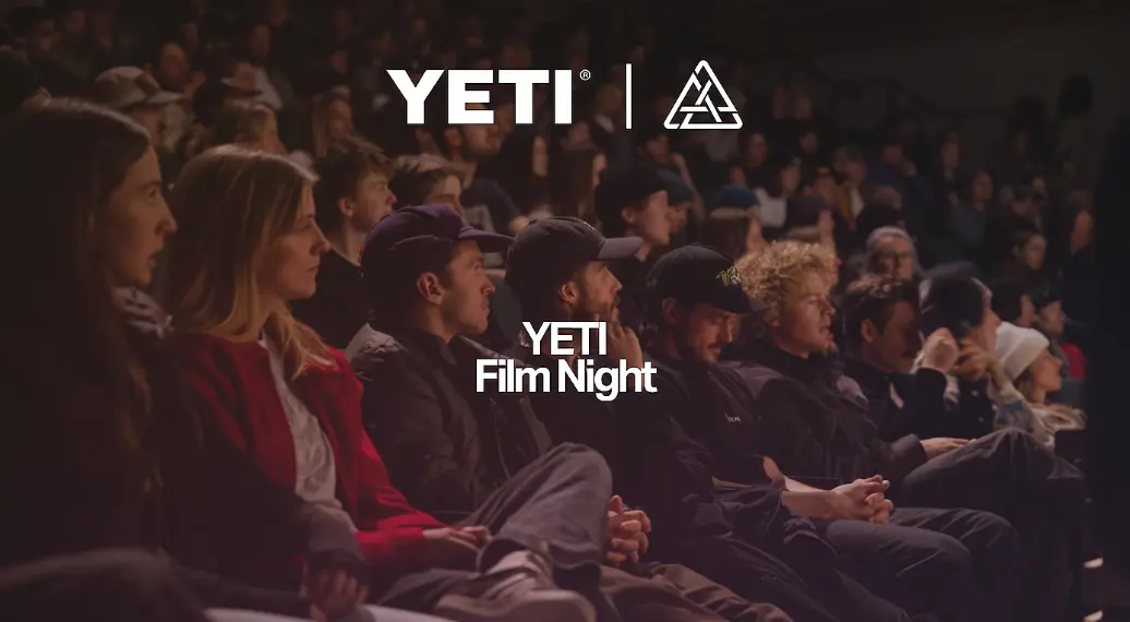 Audience seated in a dimly lit theater during YETI Film Night, with YETI logo prominently displayed above.