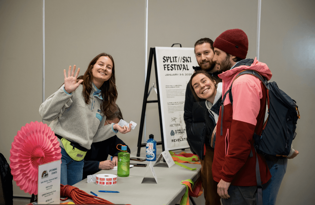 A group of people smiling at an informational booth for the Split/Skis Festival, with event posters and promotional materials on the table.