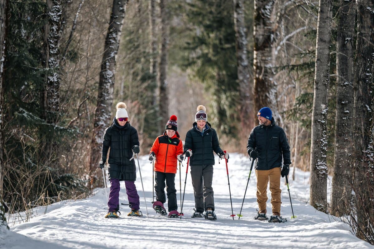 family snowshoeing on wide pathway