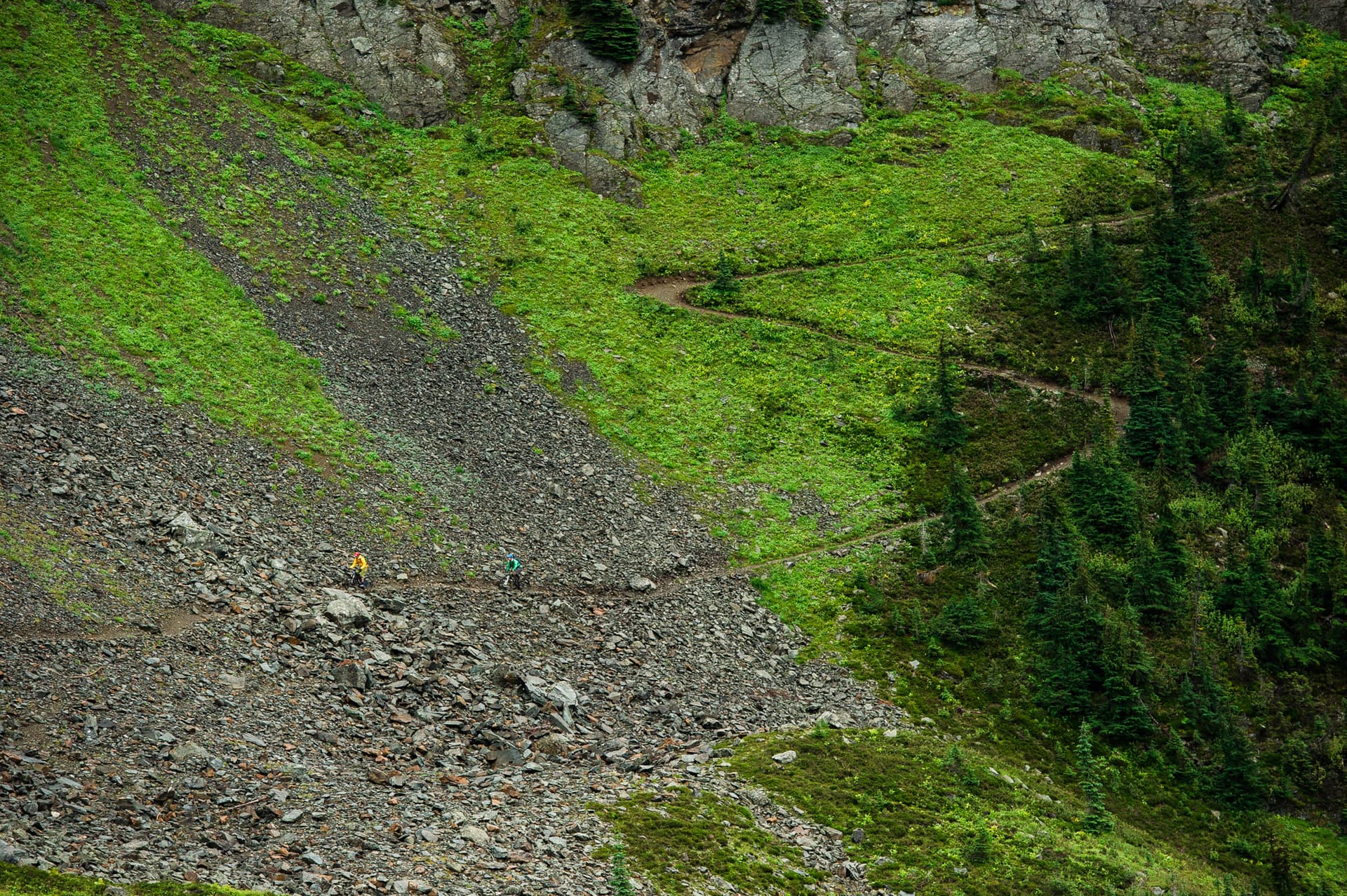 two people mountain biking along big switchback in subalpine