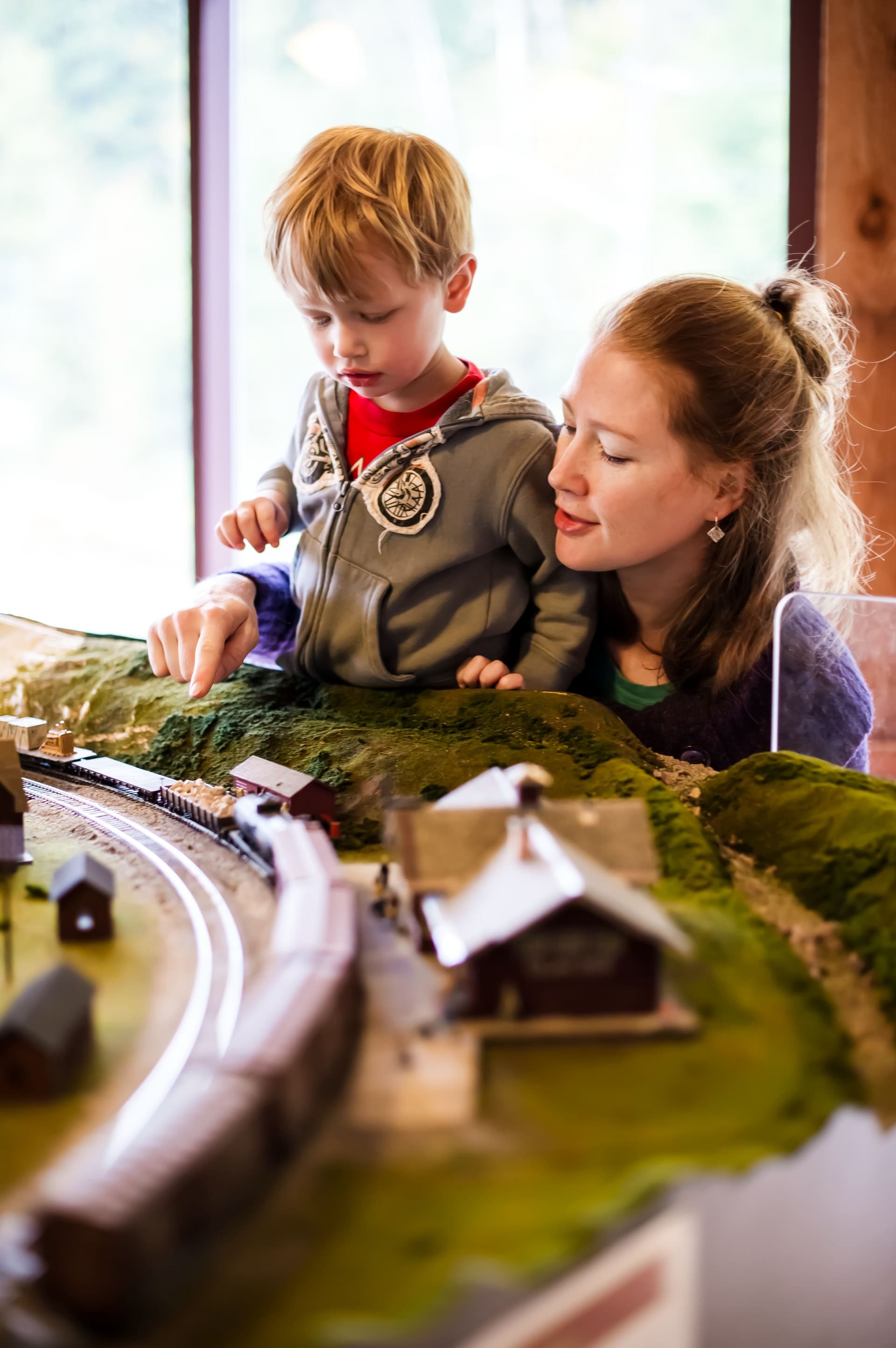 A mother and her son look closely at a model train circuit