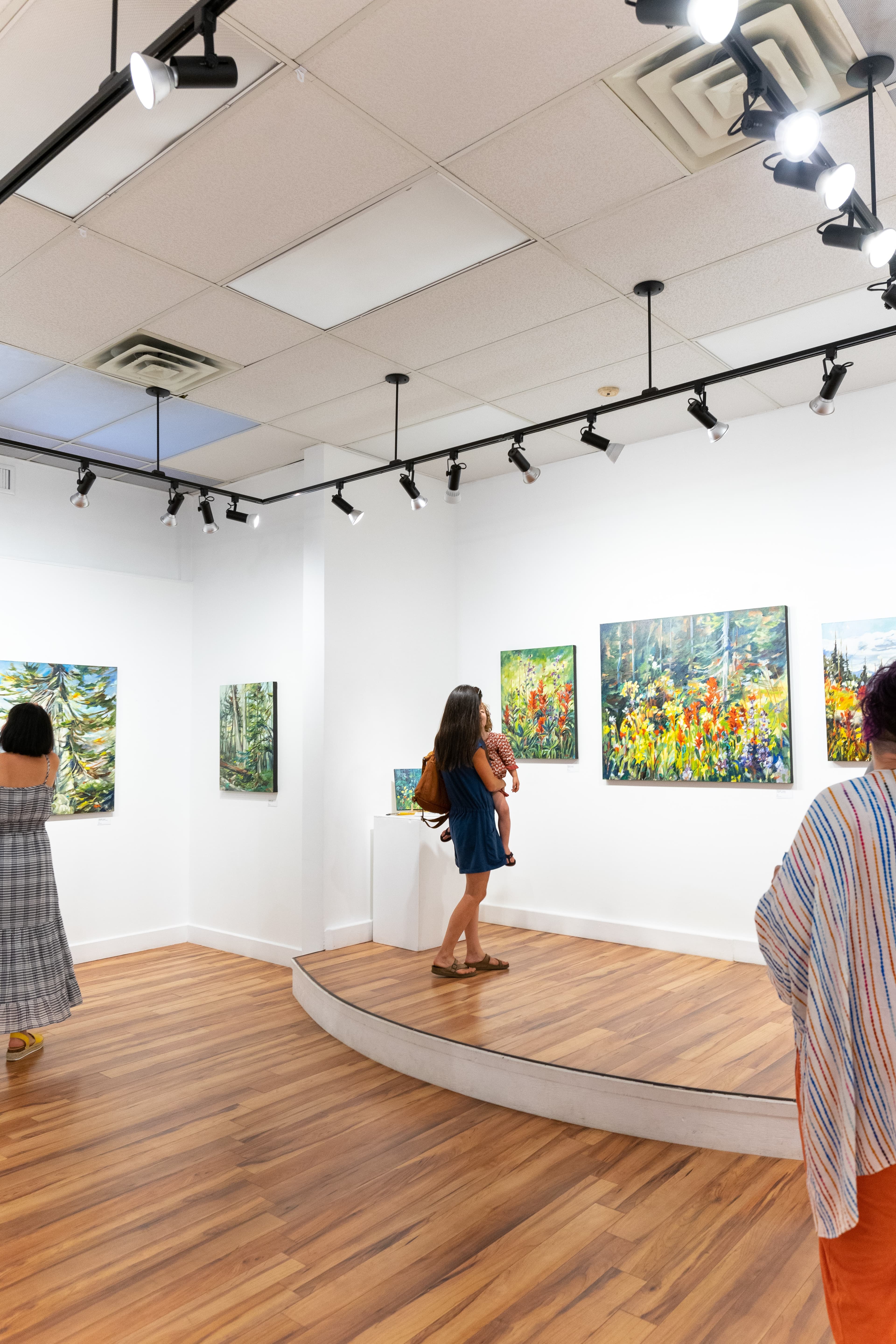people looking at wildflower paintings in art gallery