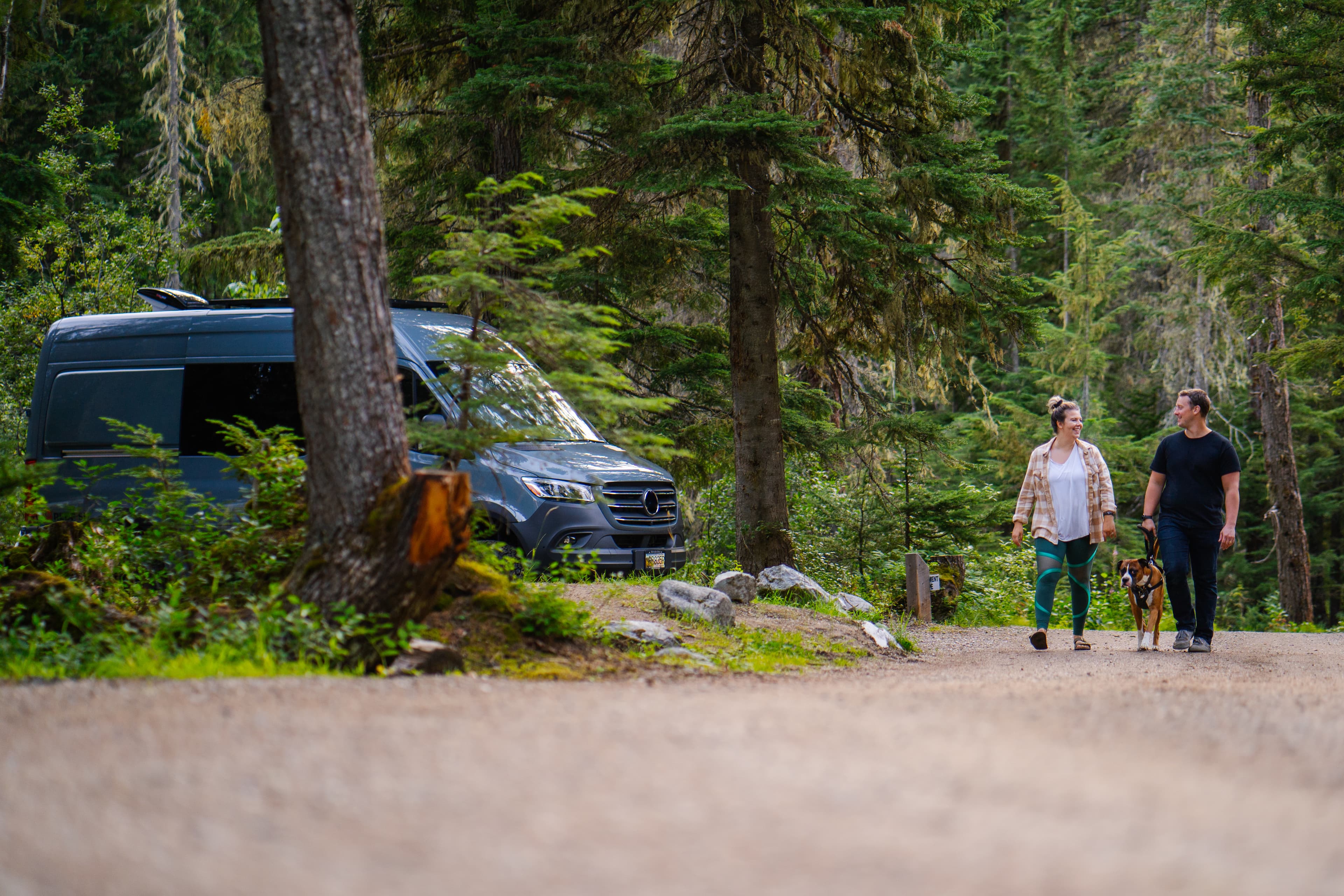 dog on leash with couple walking through campground