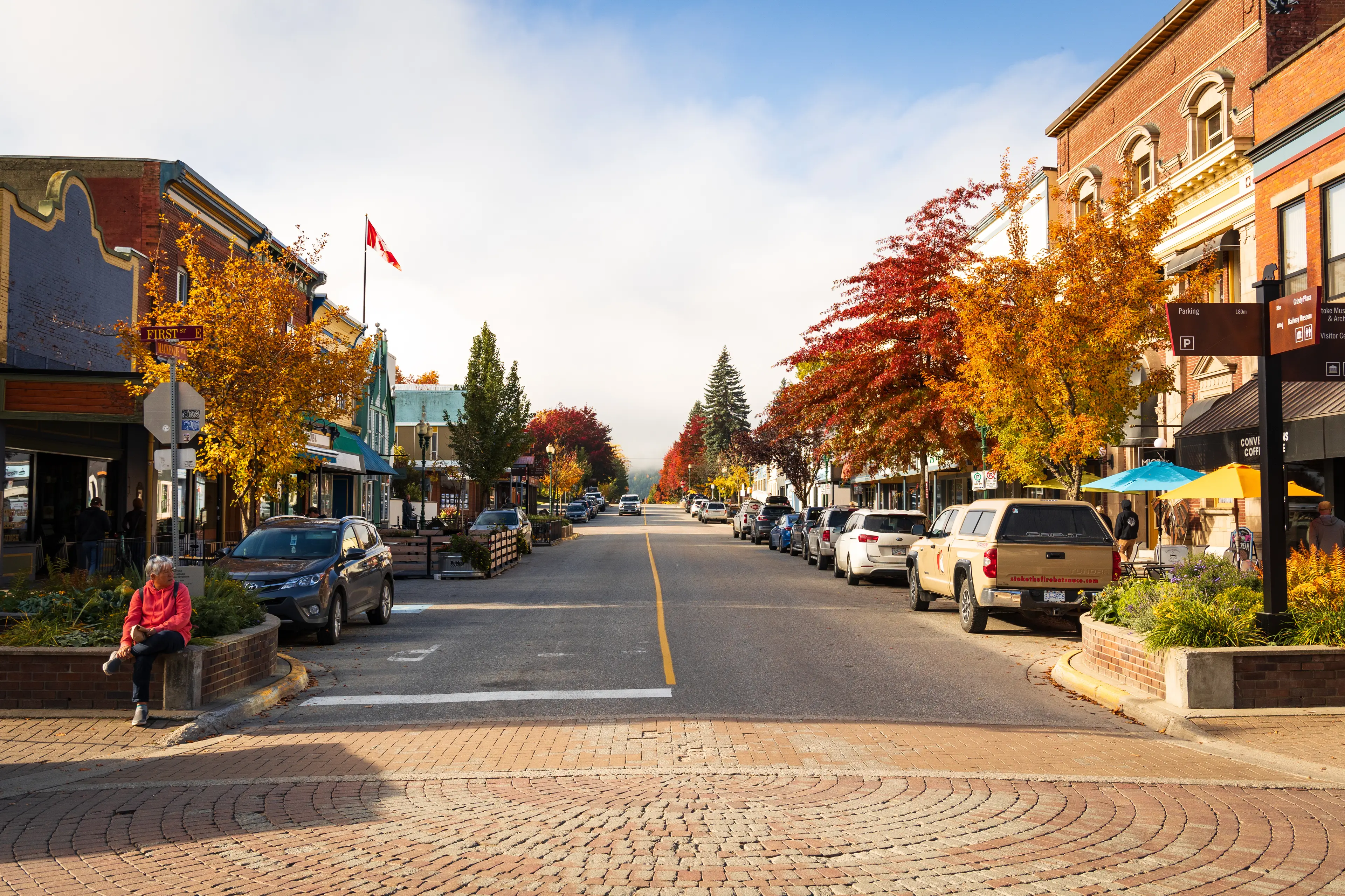 woman sitting on bench near downtown street in fall colours