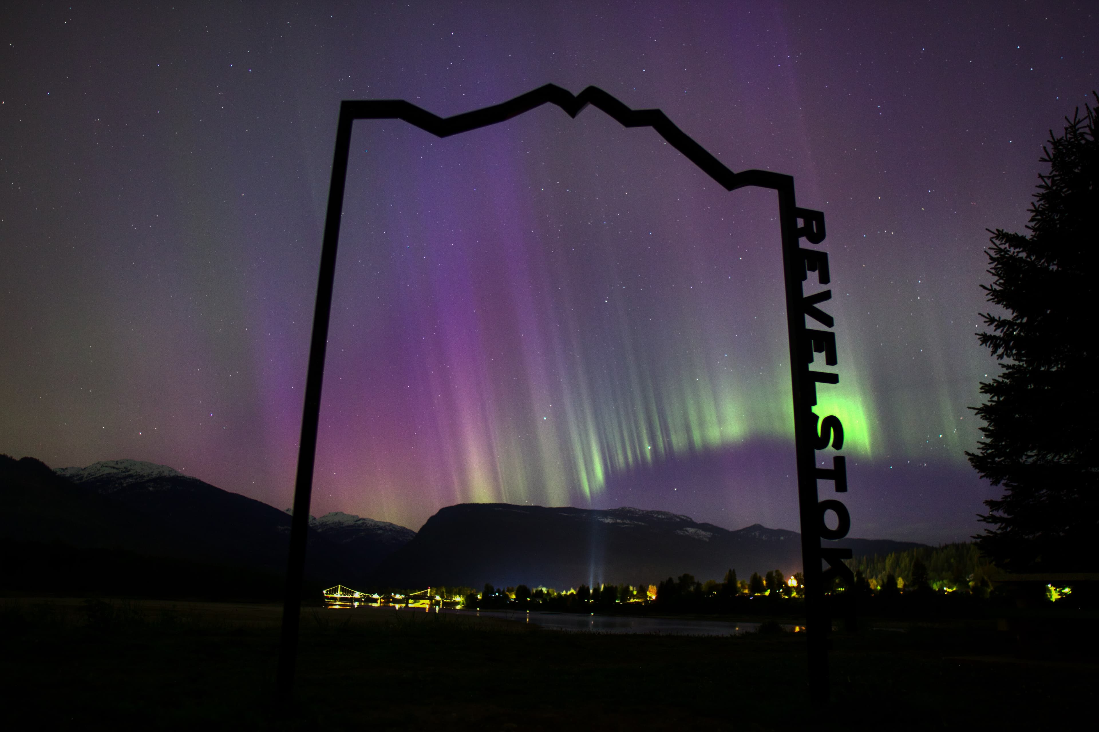 purple, green, and pink northern lights behind Revelstoke sign