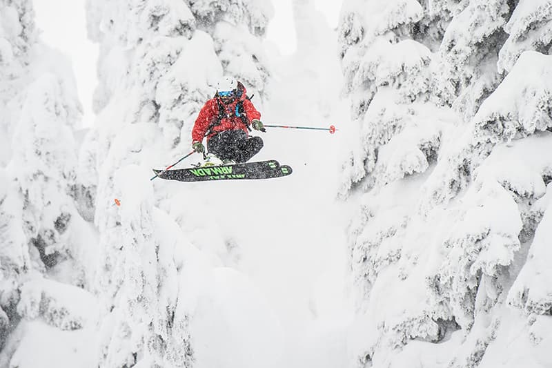 skier jumping between trees in powder conditions