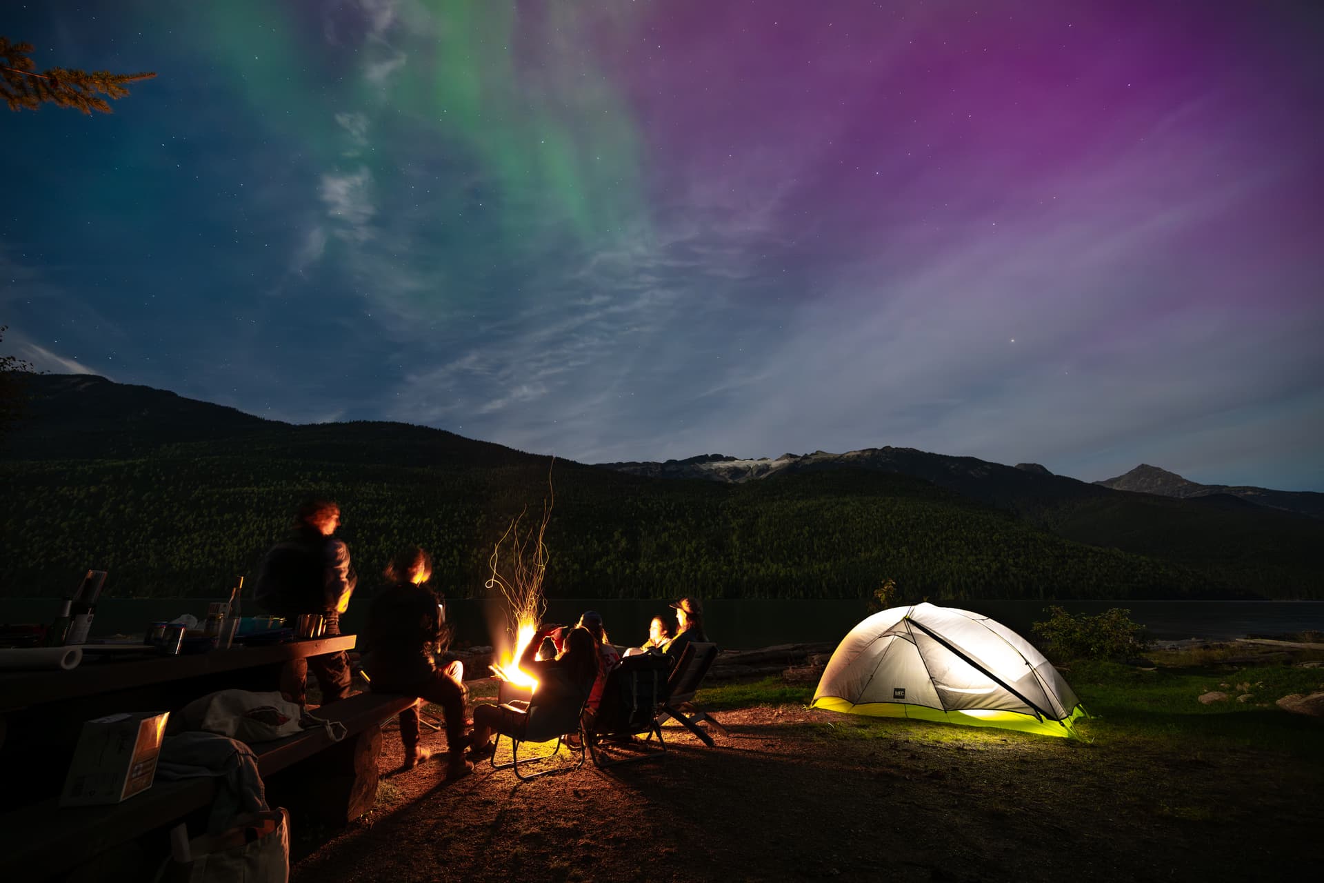 northern lights above tent and campfire