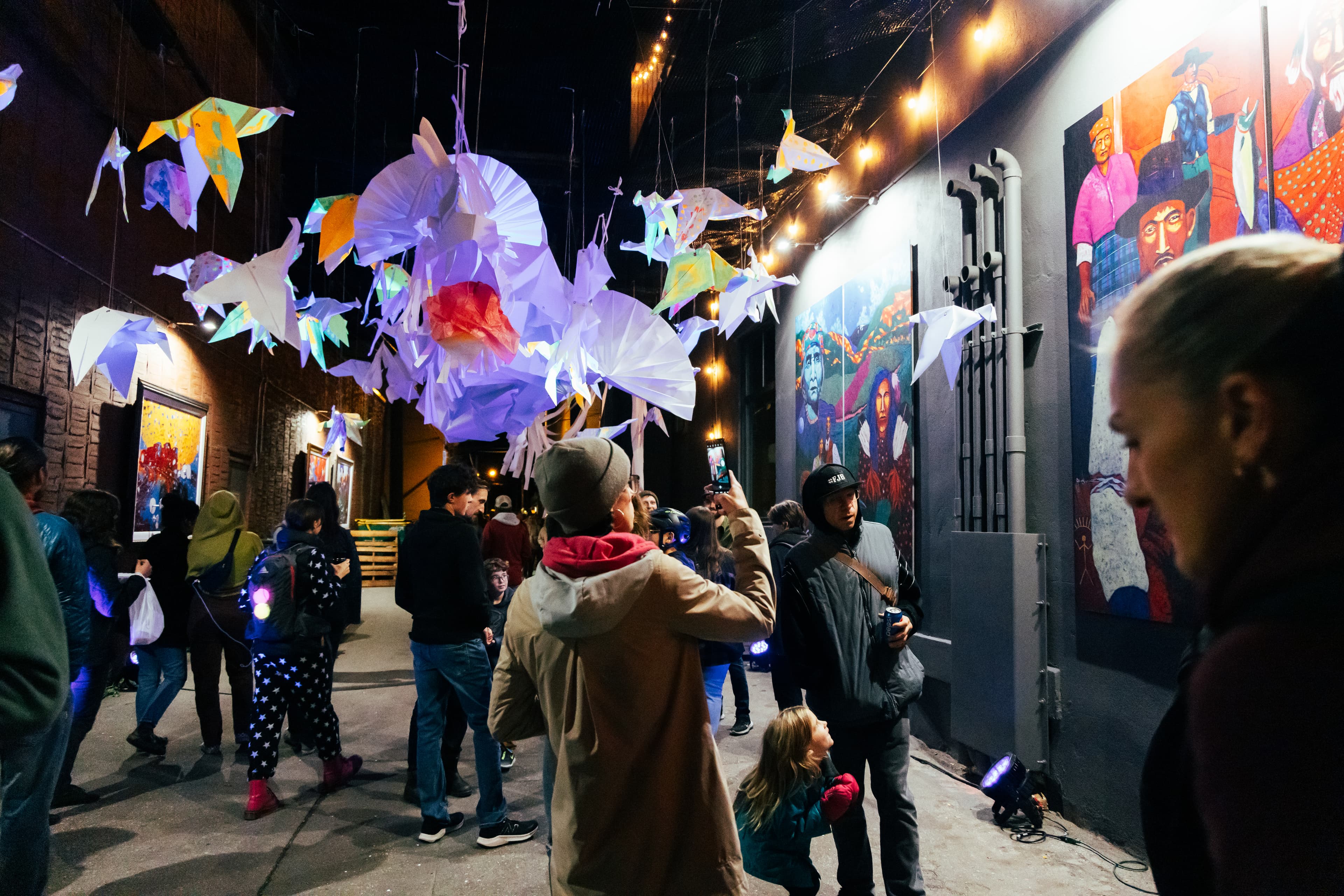 people walking underneath origami art installation