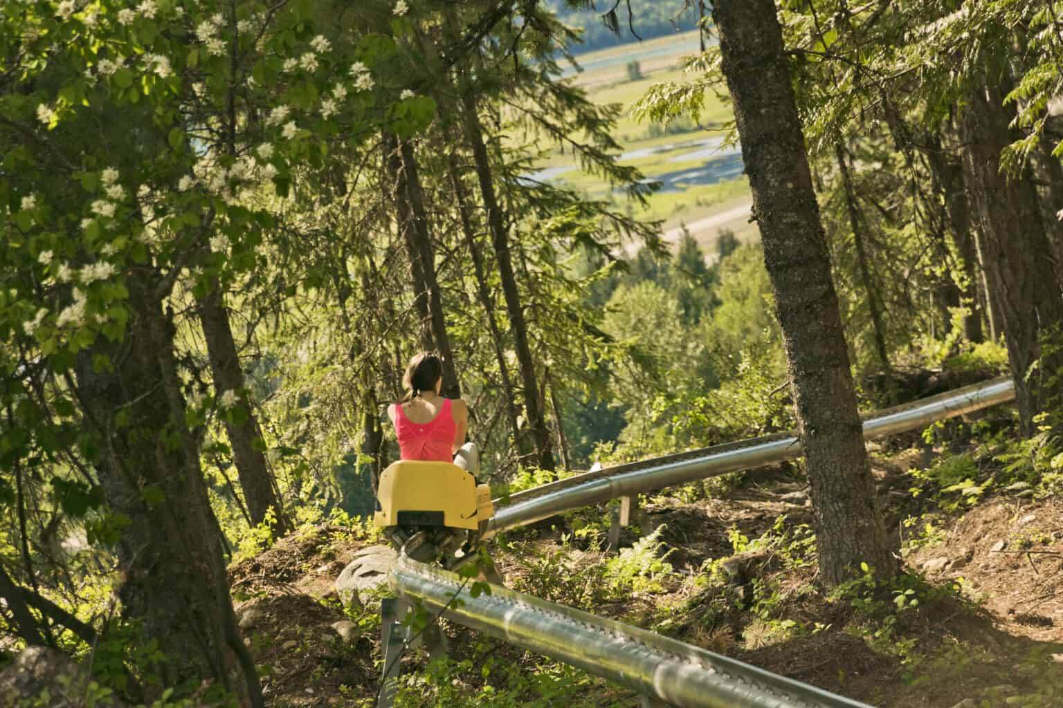 female riding pipe coaster track through forest